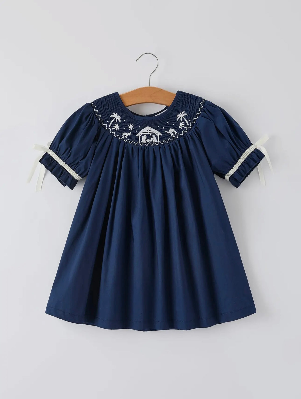 Navy blue dress with white embroidery on a hanger against a white background
