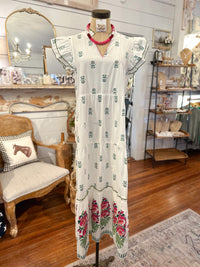 White dress with floral patterns on a mannequin in a store setting.