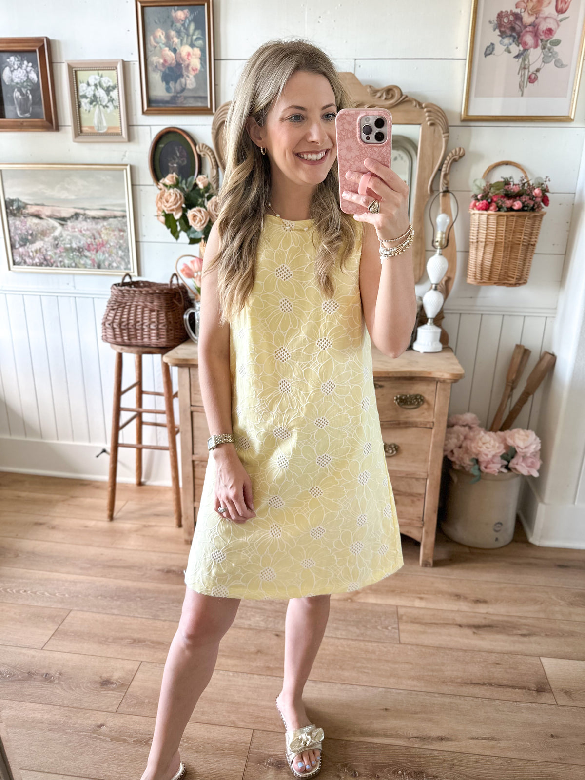 Woman taking a mirror selfie wearing a yellow dress in a home setting.