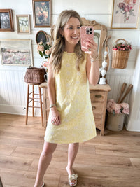 Woman taking a mirror selfie wearing a yellow dress in a home setting.