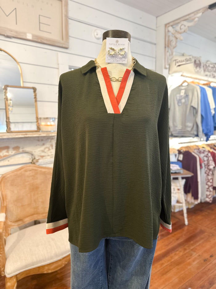 Green sleeveless top with orange and cream accents on a mannequin in a store setting.