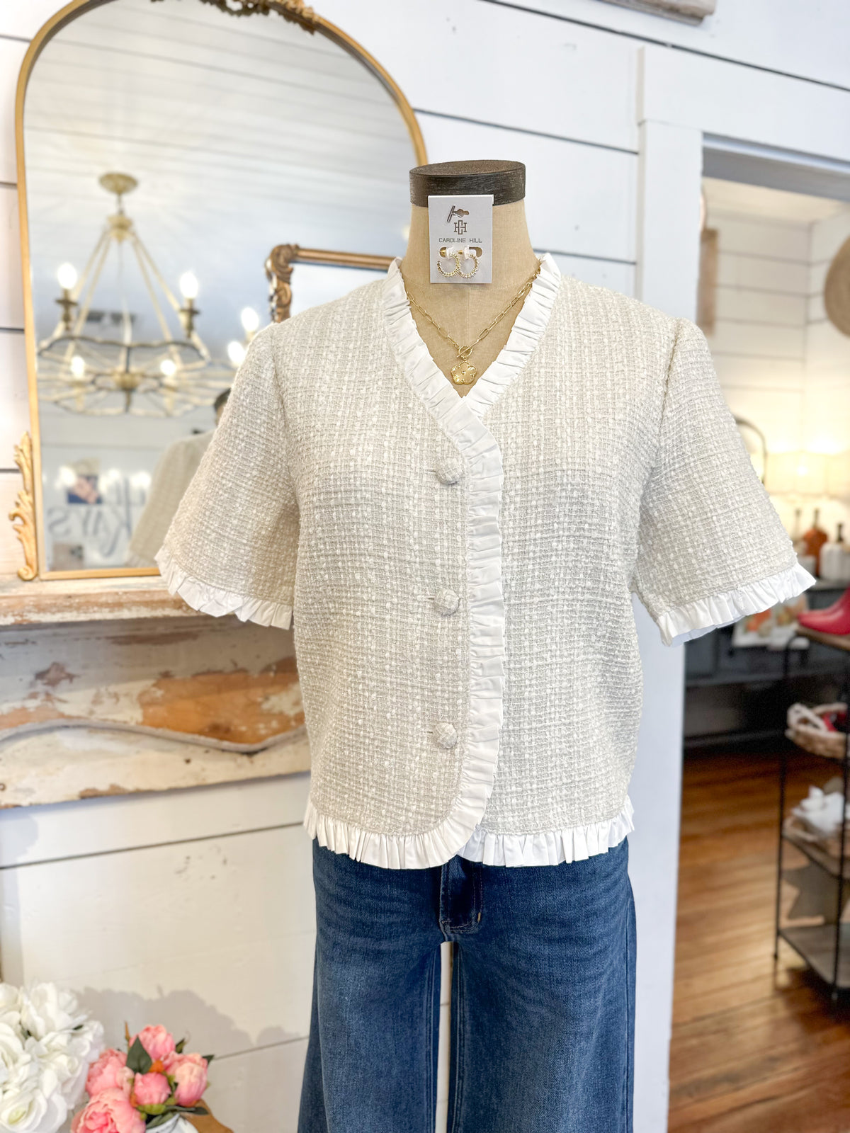 White textured short-sleeve blouse on a mannequin with blue jeans in a store setting.