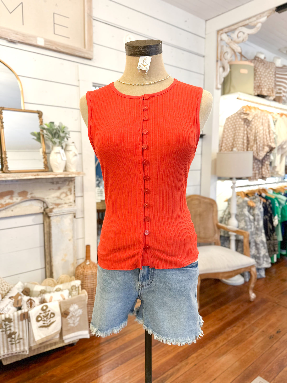 Mannequin wearing a red sleeveless top and denim shorts in a store setting.