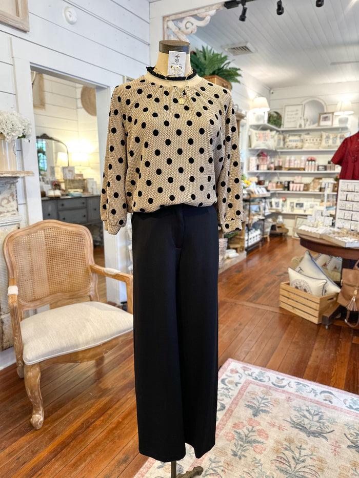 Mannequin wearing a polka dot blouse and black pants in a store setting