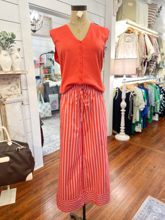 Mannequin wearing an orange top and red striped pant in a store setting