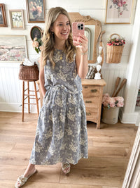 Woman taking a mirror selfie in a floral dress in a home setting.