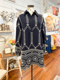 Navy blue dress with intricate white patterns on a mannequin in a store setting.