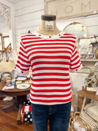 Mannequin wearing a red and white striped sweater with hearts in a home decor setting