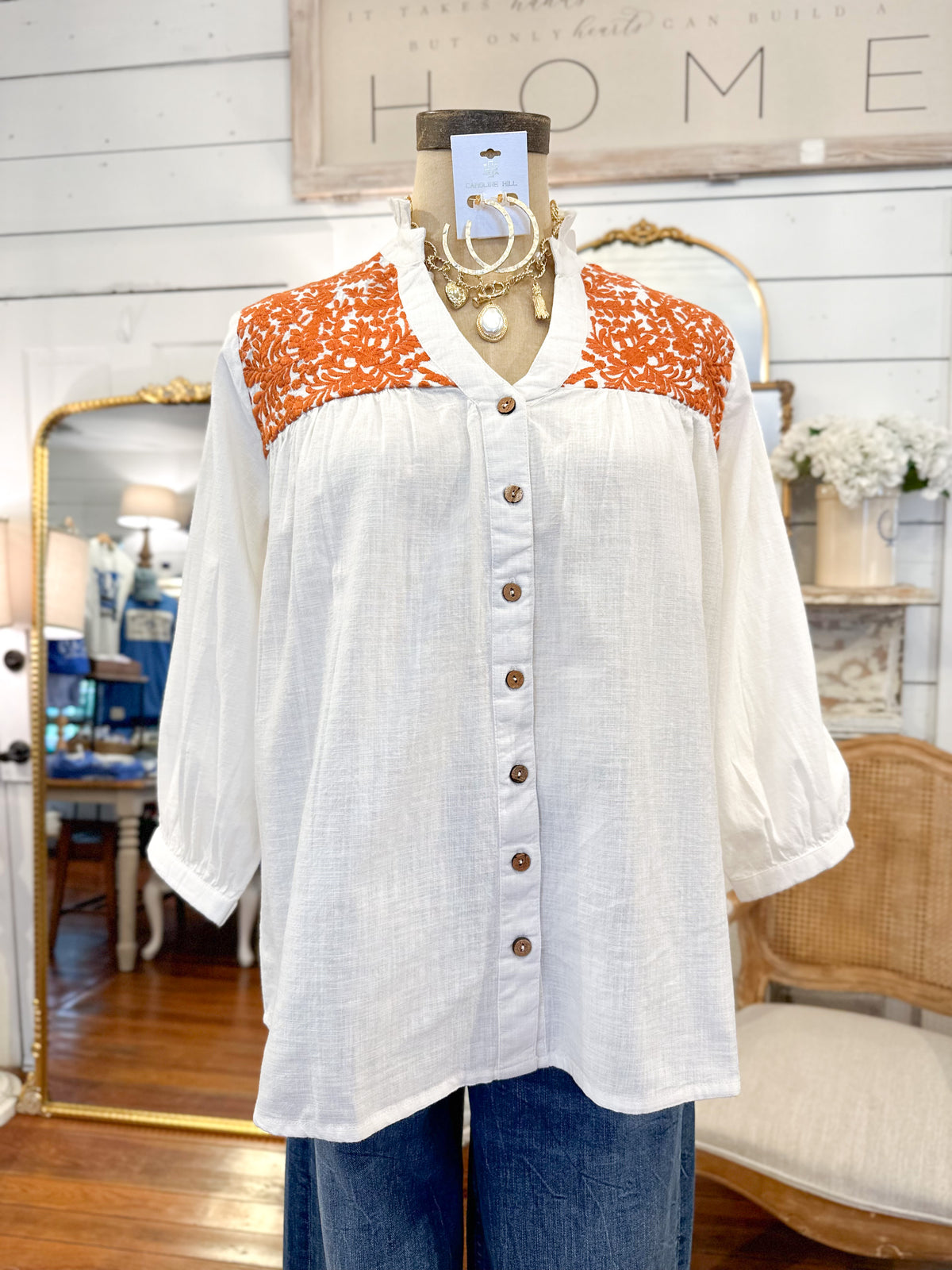 White blouse with orange pattern on a mannequin in a store setting layerz clothing jane top 
