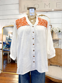 White blouse with orange pattern on a mannequin in a store setting layerz clothing jane top 