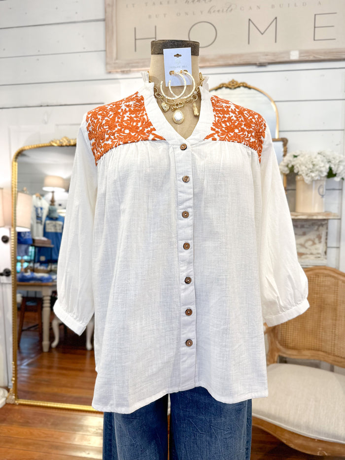White blouse with orange pattern on a mannequin in a store setting layerz clothing jane top 