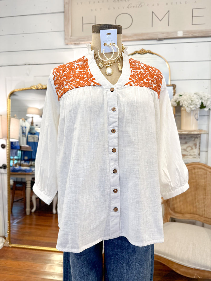 White blouse with orange pattern on a mannequin in a store setting layerz clothing jane top 