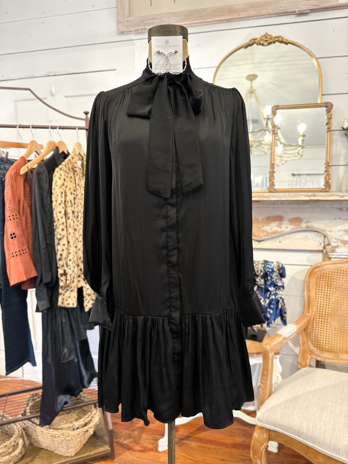 Black dress on a mannequin in a store setting with clothing racks and mirrors in the background.