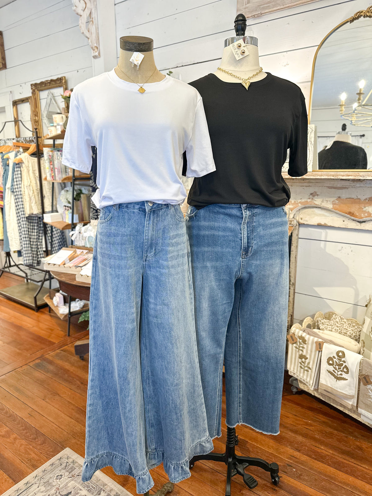 Mannequins wearing white and black shirts with blue jeans in a store setting.