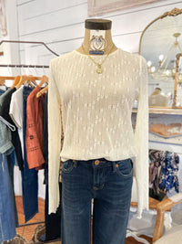 Mannequin wearing a cream sweater and blue jeans in a clothing store setting.