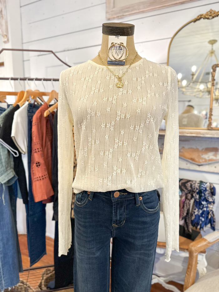 Mannequin wearing a cream sweater and blue jeans in a clothing store setting.