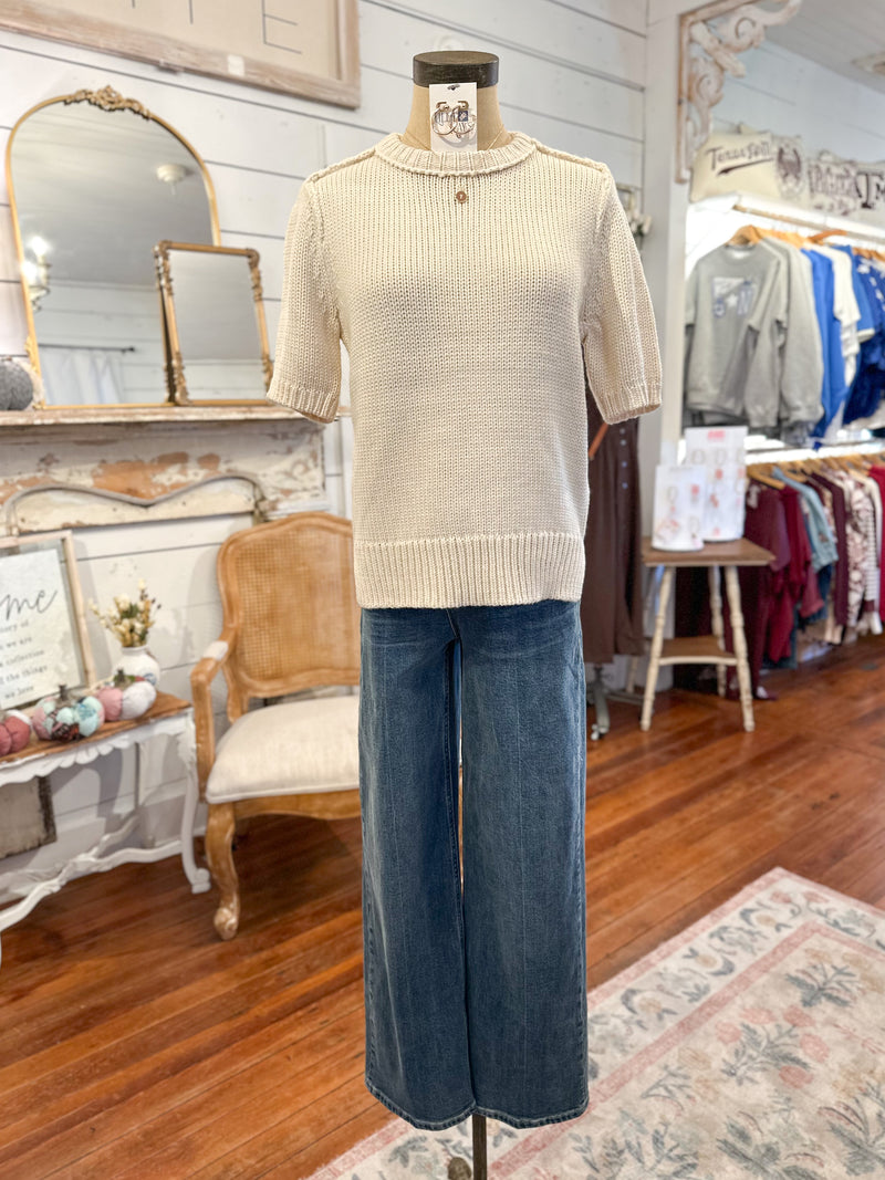Mannequin wearing a beige sweater and blue jeans in a store setting
