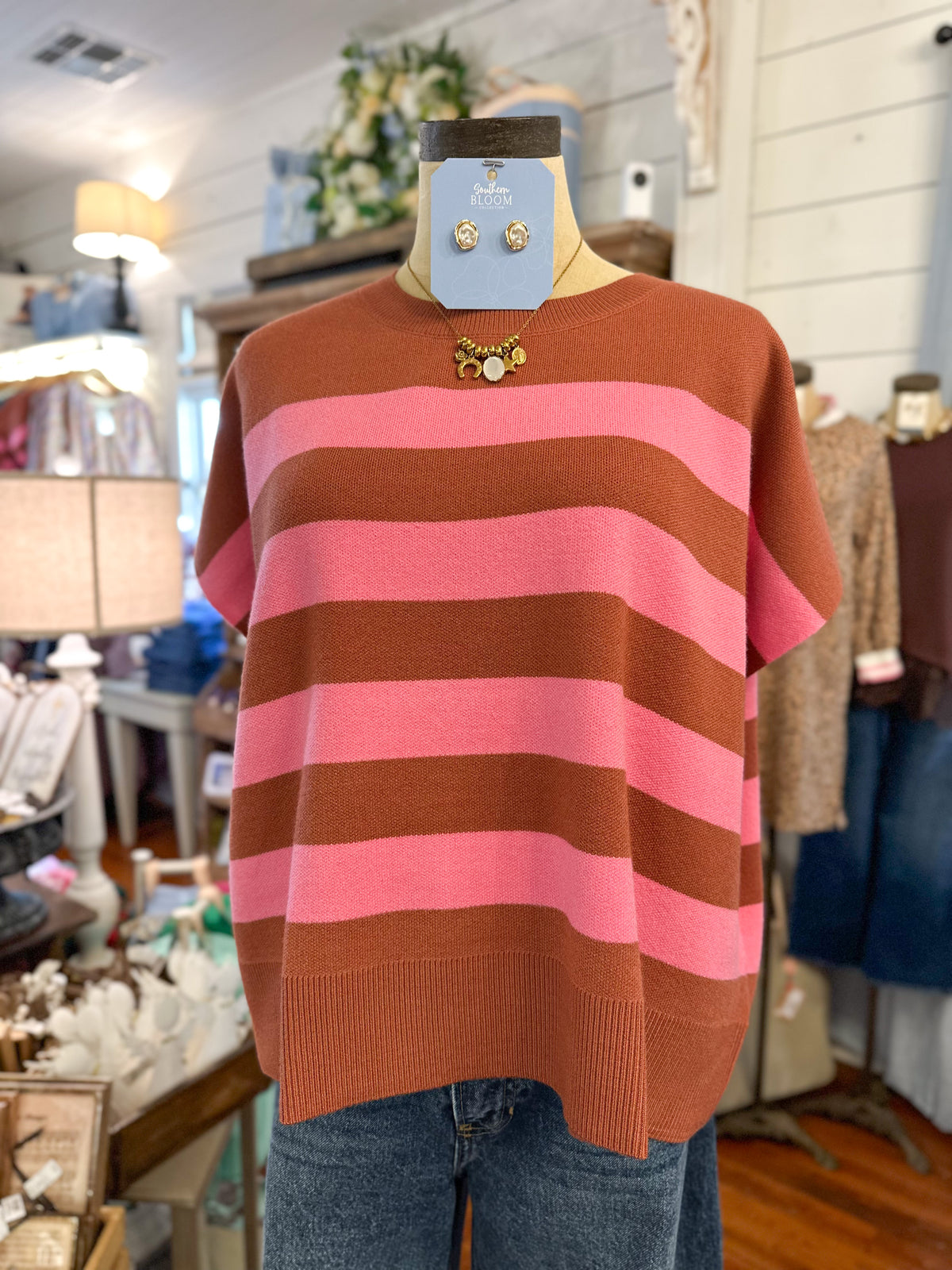 Rust and pink color striped short sleeve sweater top inside store setting 