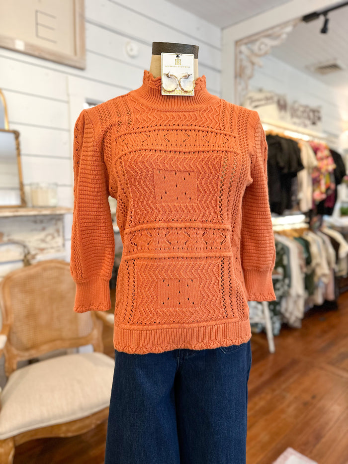 Orange sweater on a mannequin in a store setting