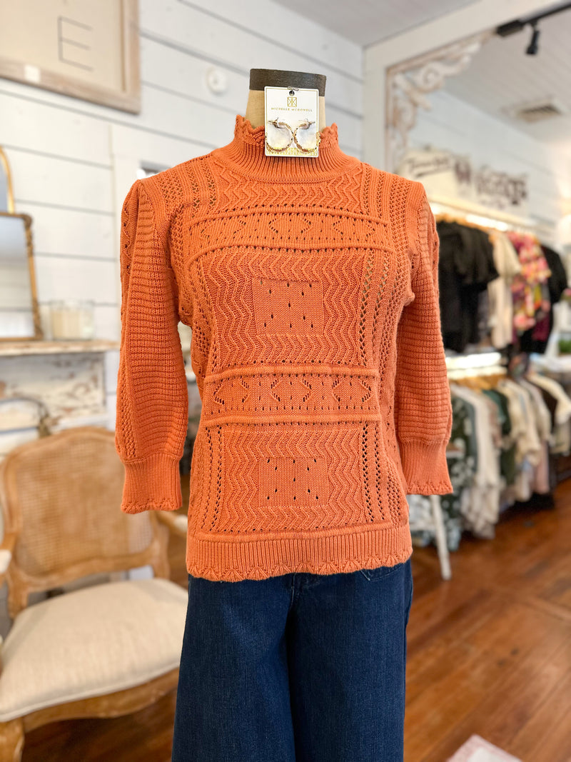 Orange sweater on a mannequin in a store setting