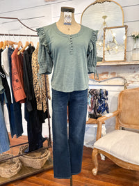 Mannequin wearing a green top and blue jeans in a clothing store setting.