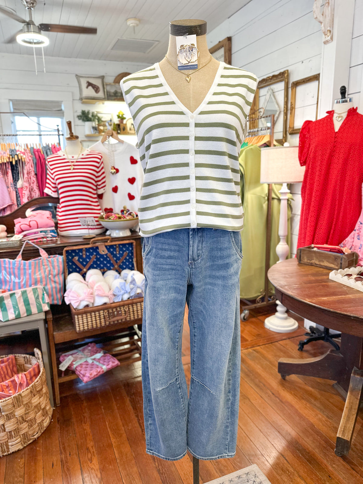 Mannequin wearing a striped shirt and jeans in a store setting with various clothing items in the background.