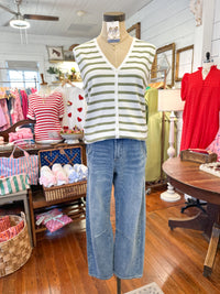 Mannequin wearing a striped shirt and jeans in a store setting with various clothing items in the background.