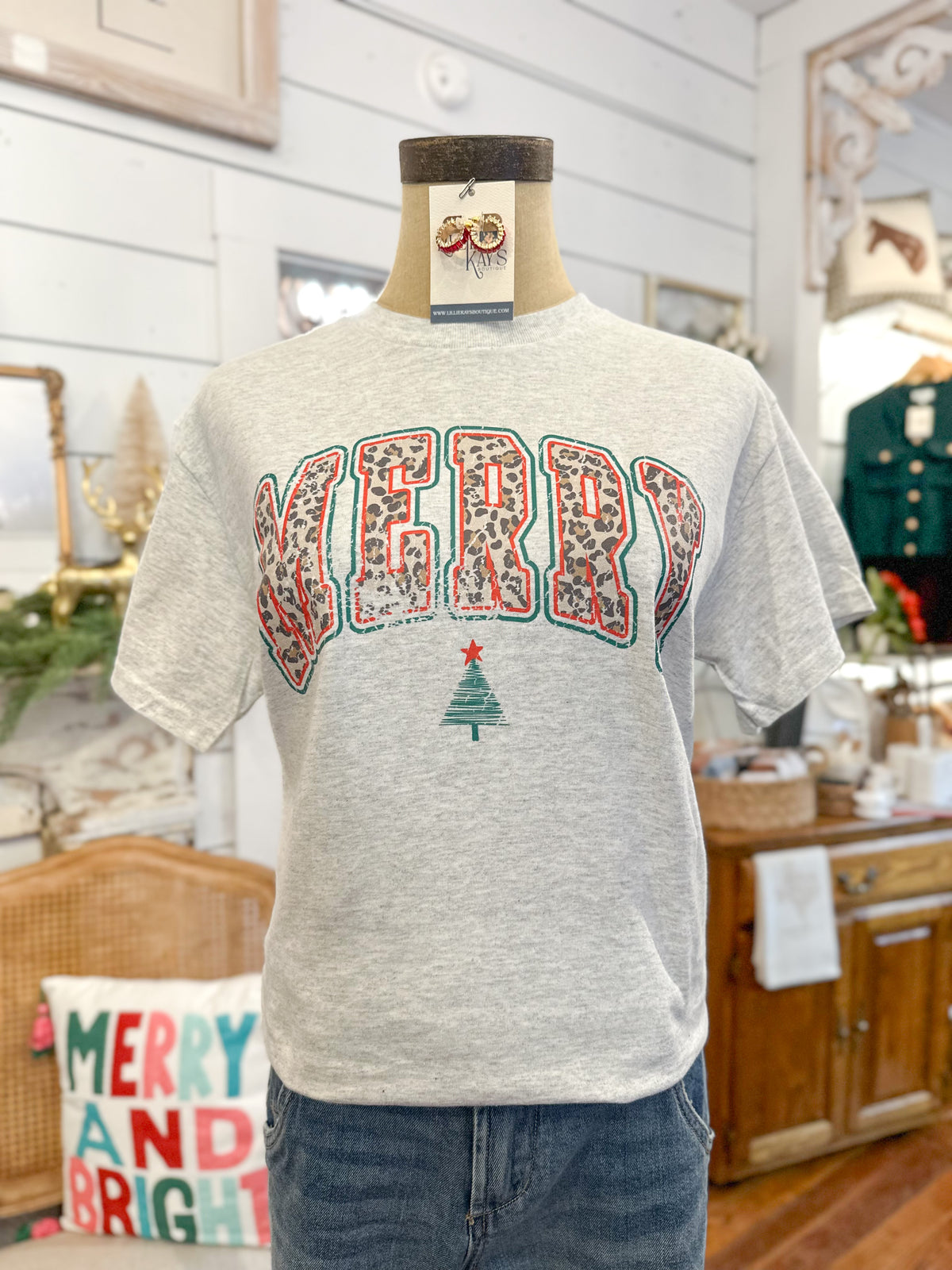 Gray t-shirt with 'Merry and Bright' design on a mannequin in a home setting.