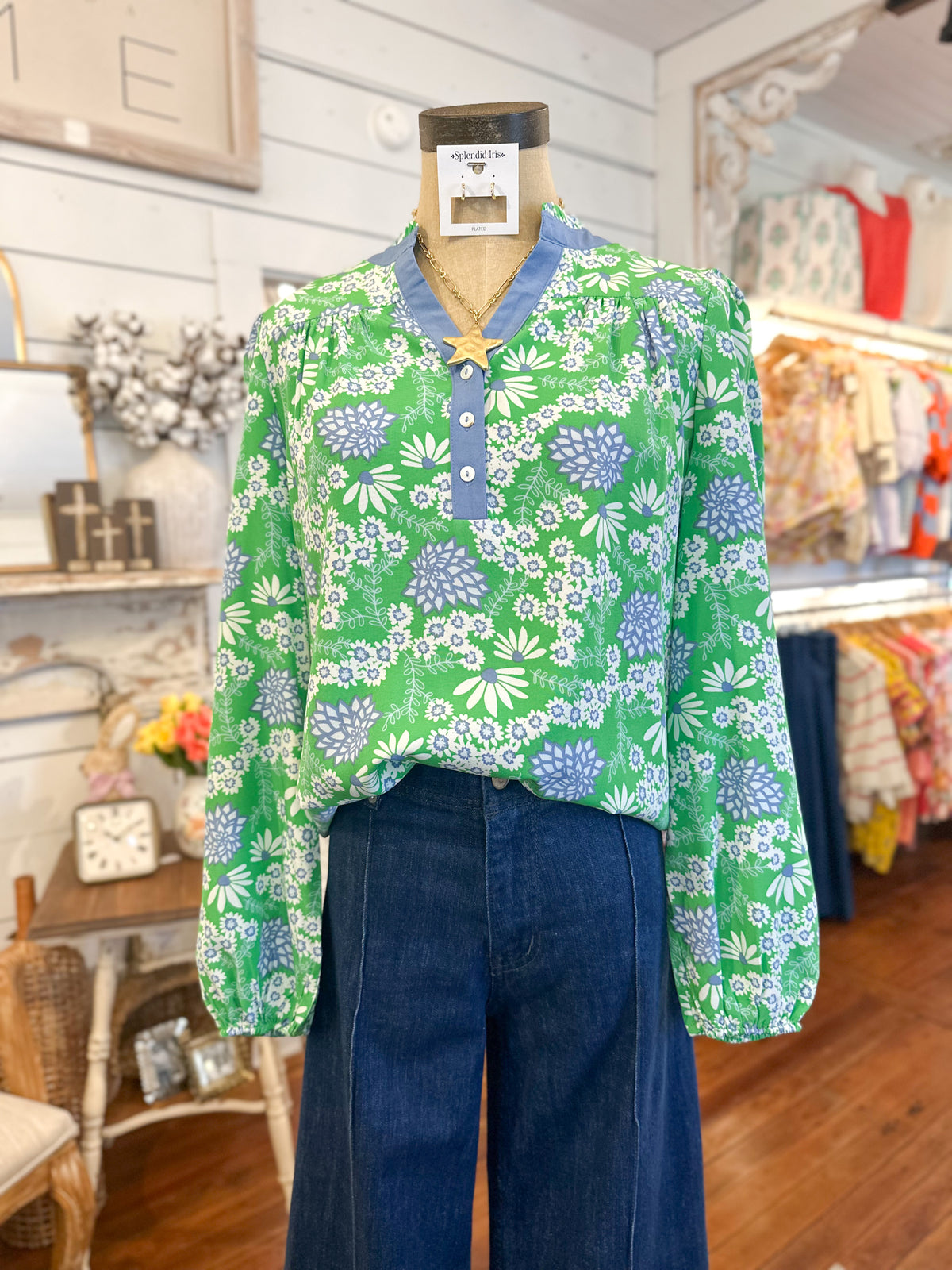 Green floral blouse on a mannequin with blue pants in a store setting