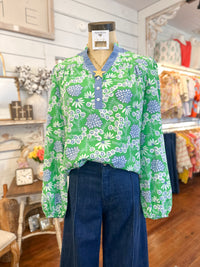 Green floral blouse on a mannequin with blue pants in a store setting