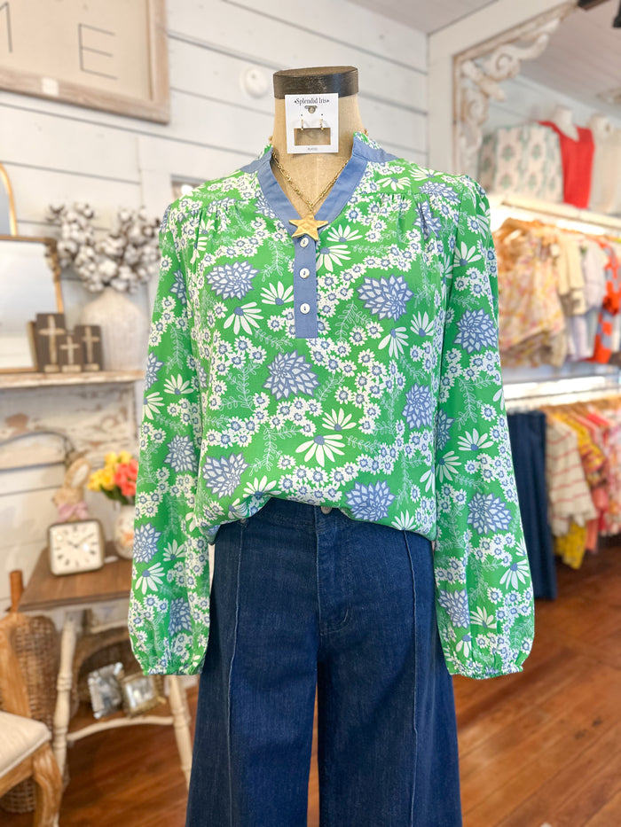 Green floral blouse on a mannequin with blue pants in a store setting