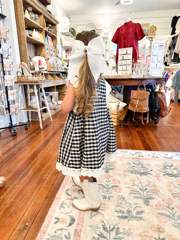 Little girl wearing black and white plaid dress with white boots 
