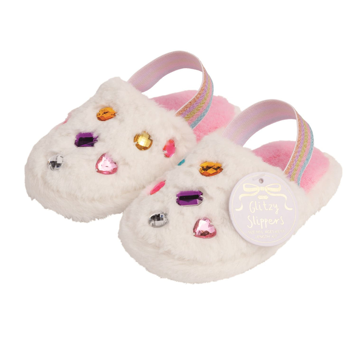 A pair of white fuzzy toddler slippers decorated with colorful rhinestones, featuring pastel pink straps with rainbow stripes and a round white hangtag that reads 'Glitter Slippers'.