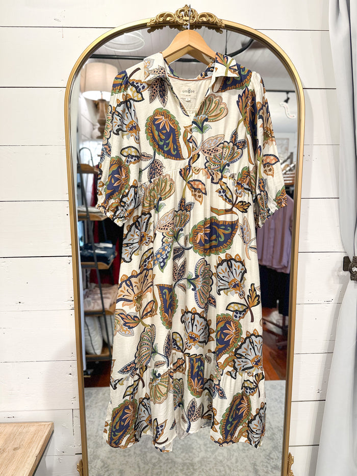 Patterned dress hanging on a mirror with a wooden frame.