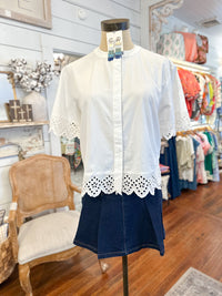 White blouse with lace details on a mannequin in a store setting