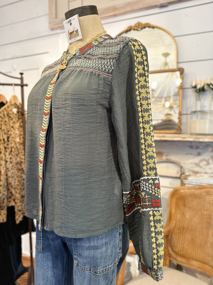 Mannequin wearing a green blouse with patterned sleeves in a store setting