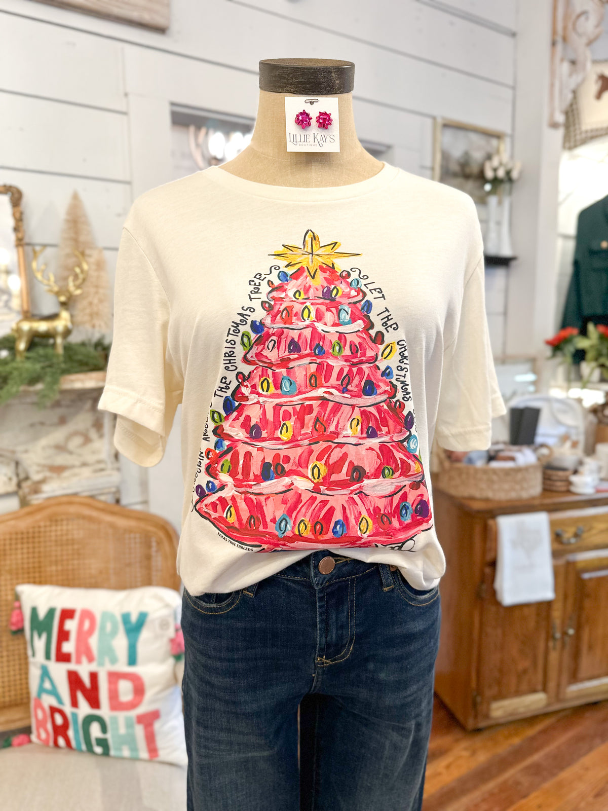 Mannequin wearing a t-shirt with a colorful Christmas tree design in a home setting.