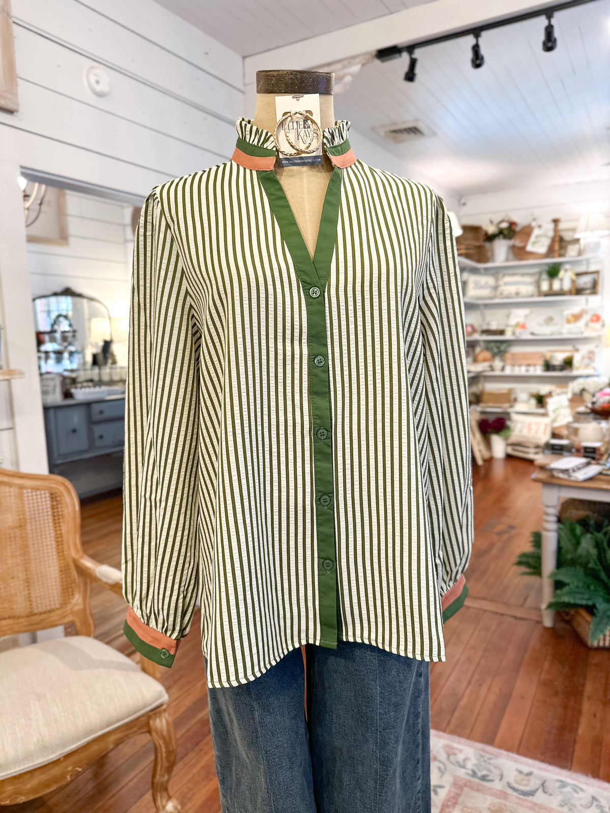 Striped shirt with green trim on a mannequin in a store setting