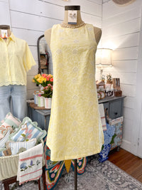 Mannequin wearing a yellow lace dress in a home setting with decor items.