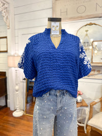 Blue textured top on a mannequin with polka dot pants in a home decor setting