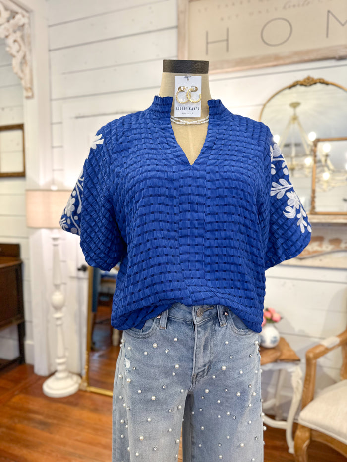 Blue textured top on a mannequin with polka dot pants in a home decor setting