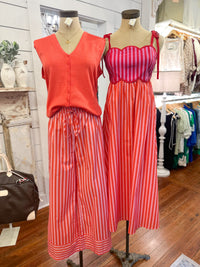 Two mannequins wearing red and pink striped outfits in a store setting.