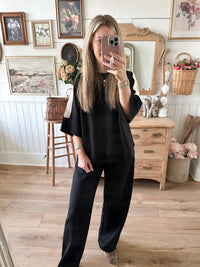 top untucked black loungewear set inside store setting pants 

