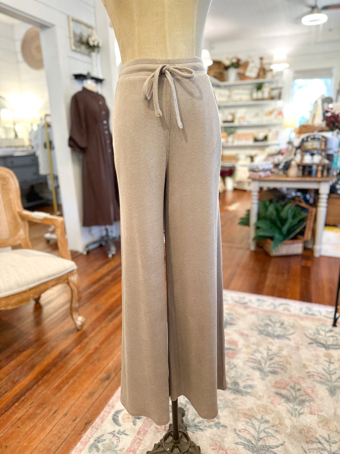 Beige pants on a mannequin in a store setting with wooden floors and furniture.