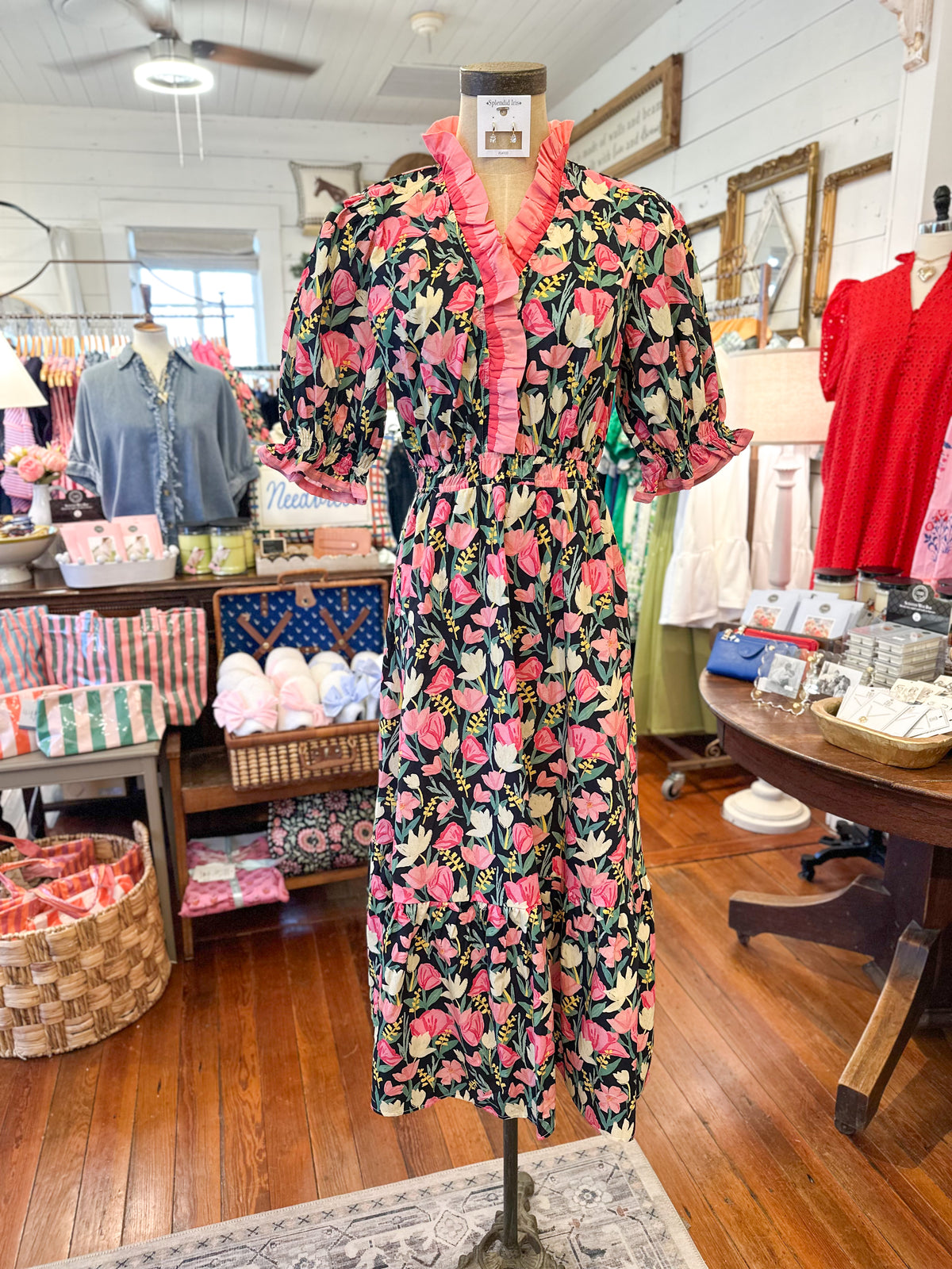 Floral dress on a mannequin in a store setting with various items in the background.