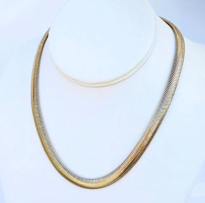 A gold-toned  chain necklace displayed on a white neck mannequin bust against a light background.