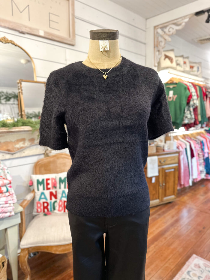 Mannequin wearing a dark black fuzzy  sweater in a store setting