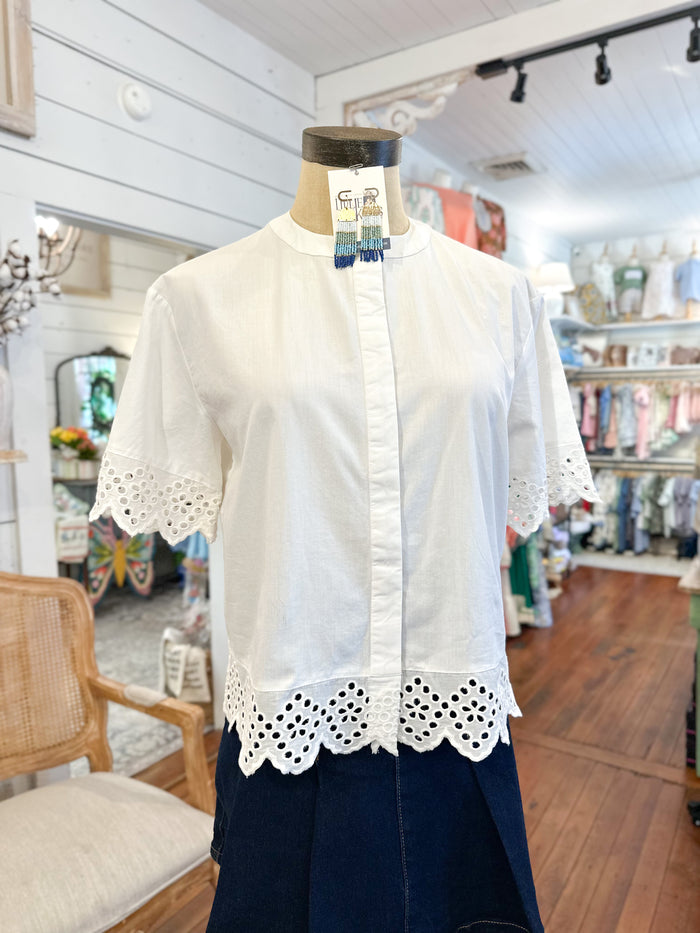 White lace-trimmed blouse on a mannequin in a store setting