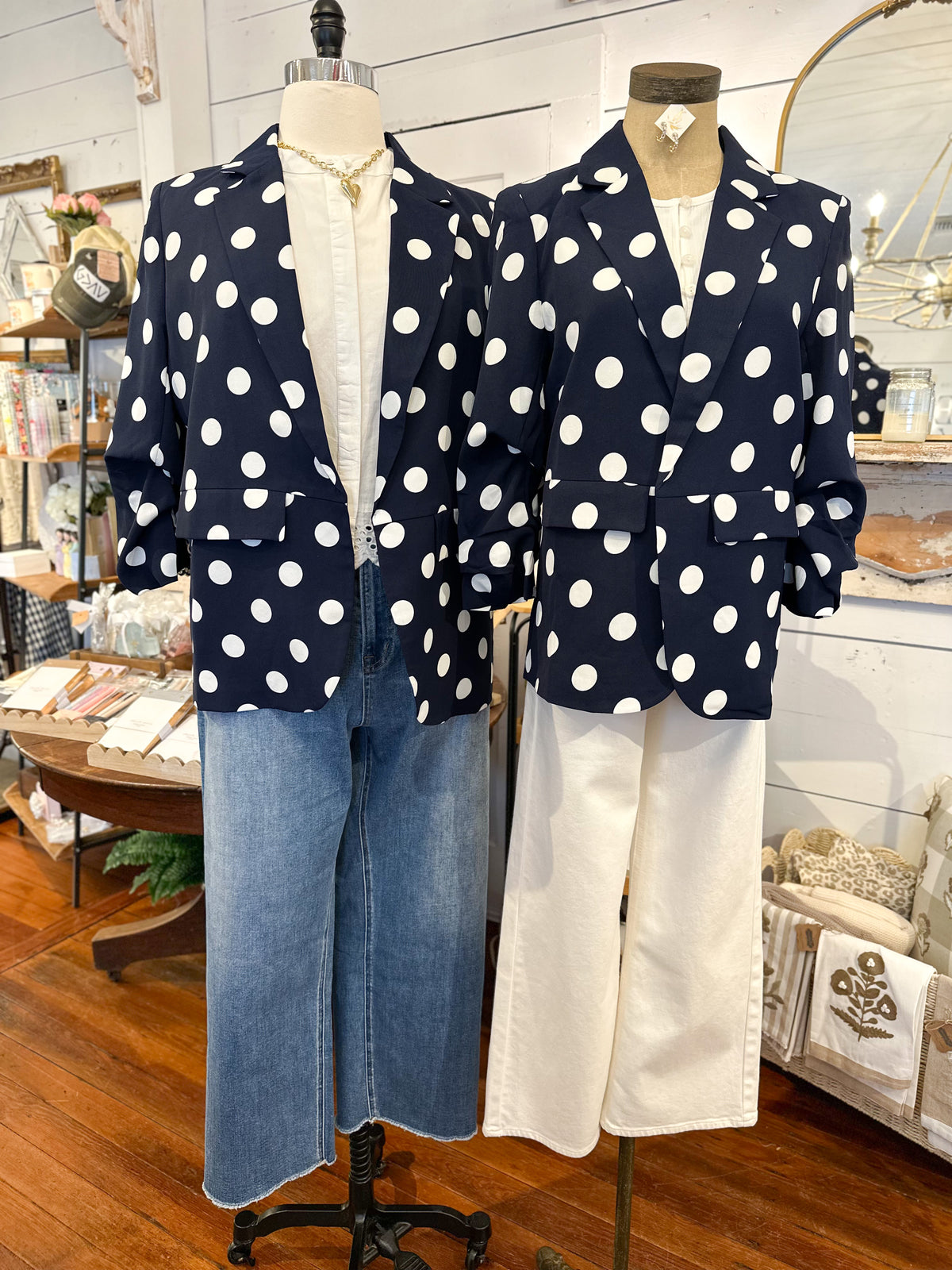 Two mannequins wearing navy blazers with white polka dots in a store setting.