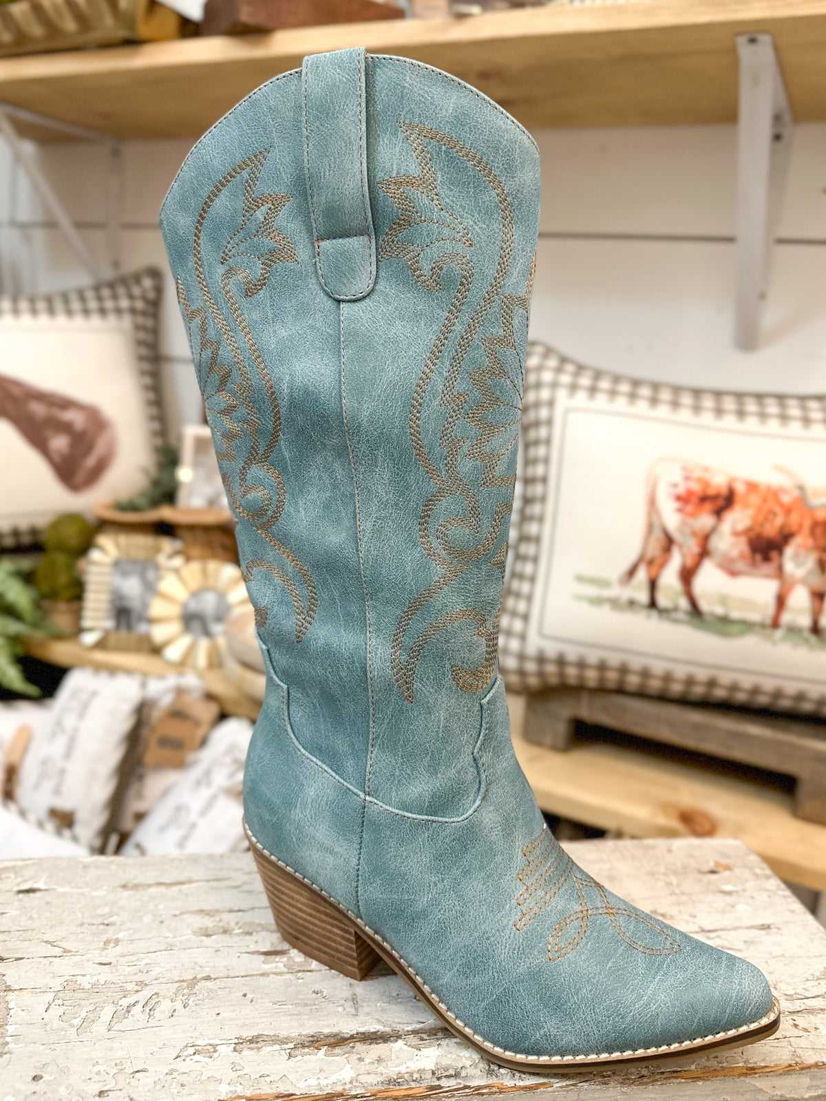 Blue cowboy boot with intricate designs on a wooden surface.